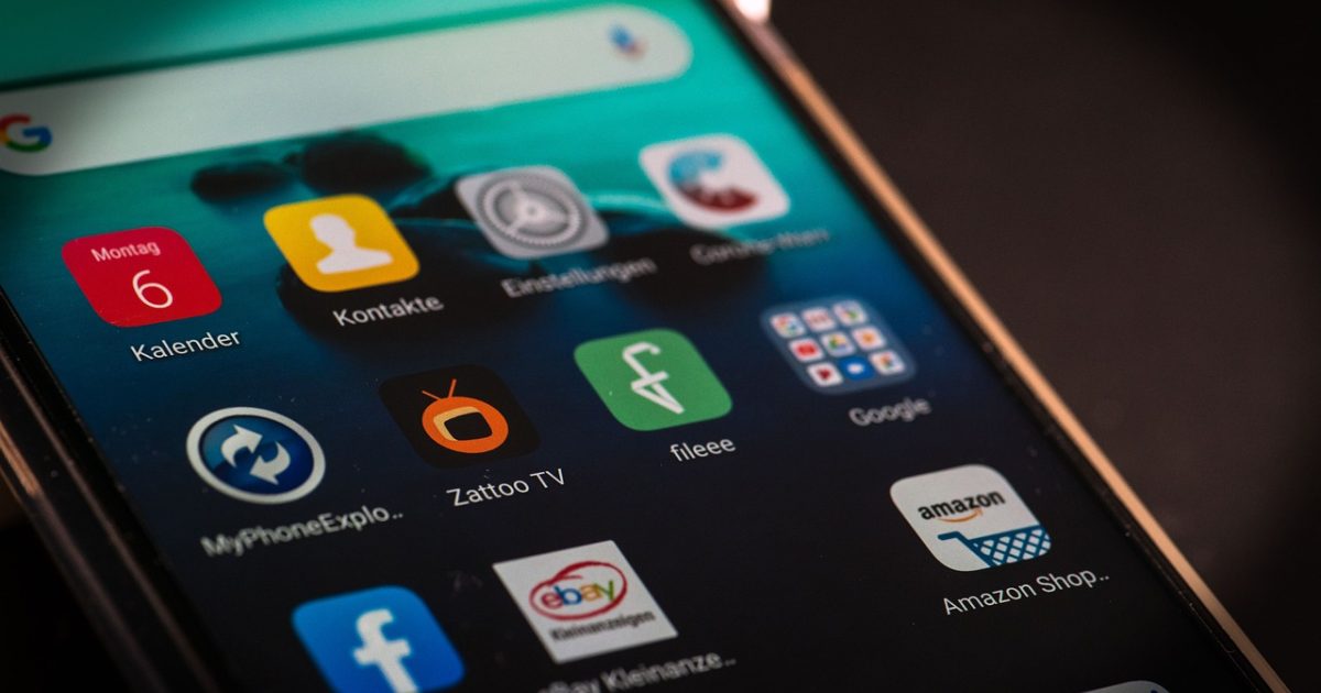 金价实时 App 主界面在手机屏幕上的展示，深绿底色上排列着黄金、铂金与白银三路报价卡片，数字带涨跌箭头，背景是全宽的黑金渐变几何纹理，整体氛围沉稳高端